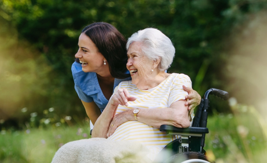 verpleegster met oude dame in rolstoel die glimlachen
