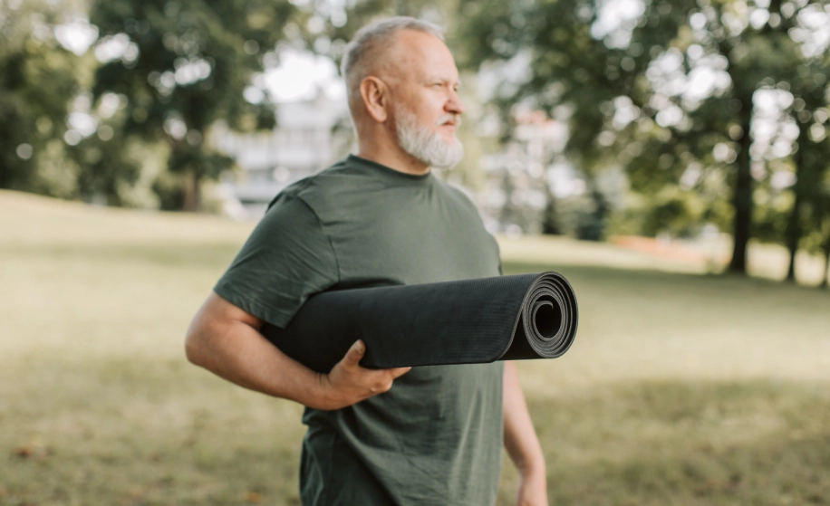 oudere man met yogamat in de hand