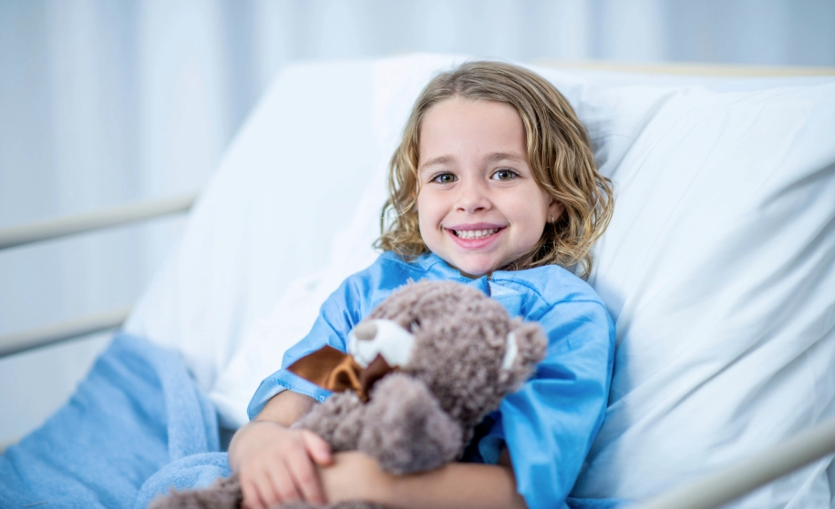 kindje in ziekenhuisbed met knuffel